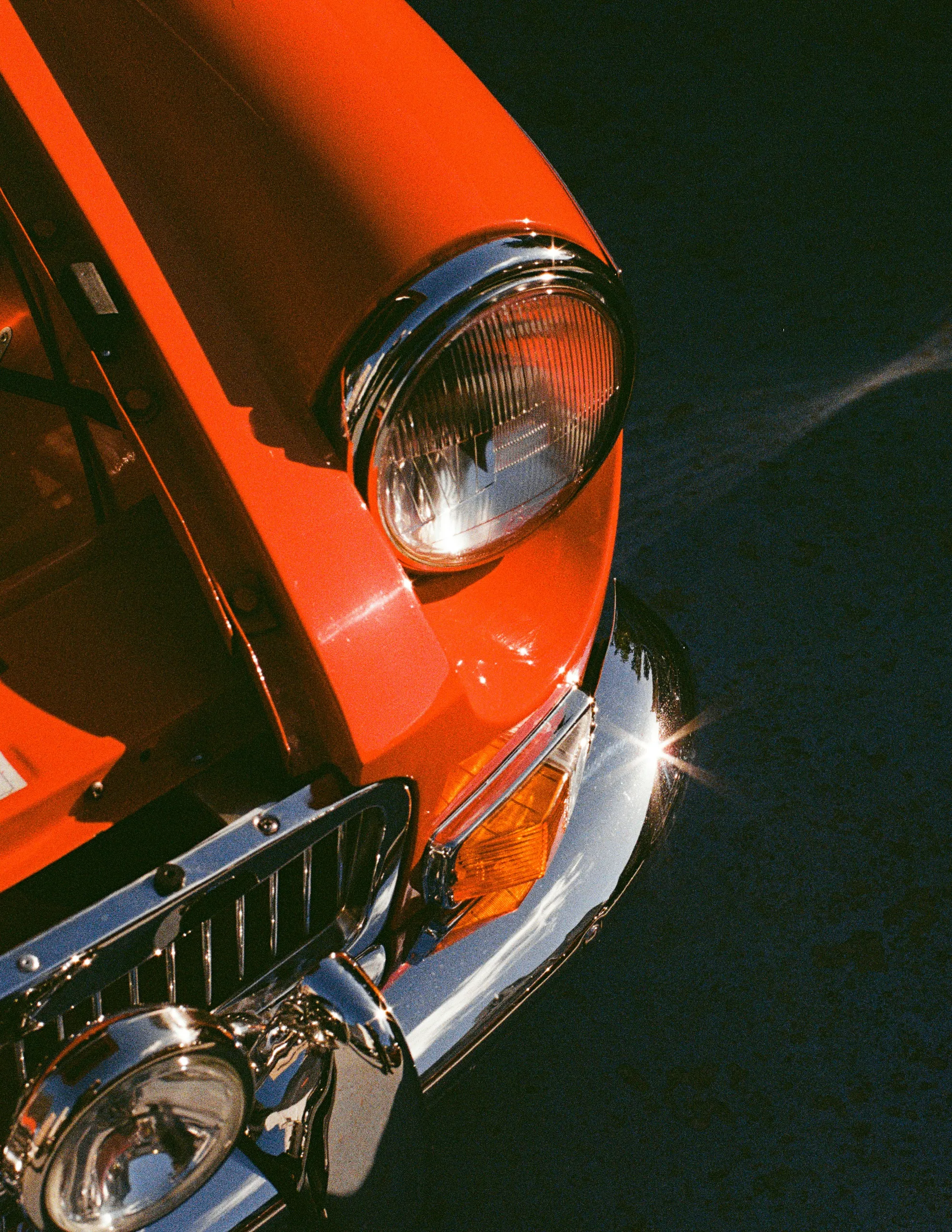 Pomarańczowe klasyczne auto, detal przodu i reflektora po detailingu